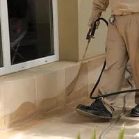 General pest control technician spraying exterior perimeter around a home in Birmingham, AL