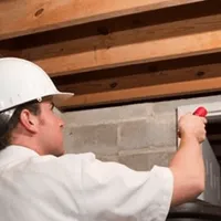 Termite inspection technician checking a basement wall and framing for termite activity in Birmingham, AL